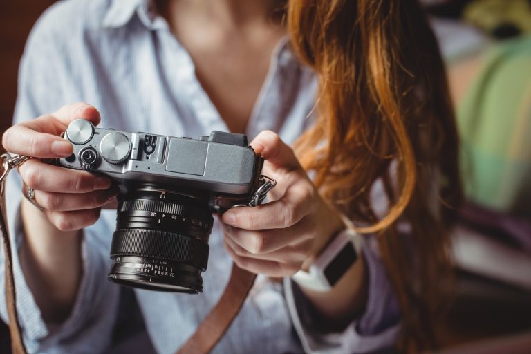 mid section of woman looking at pictures on digital camera