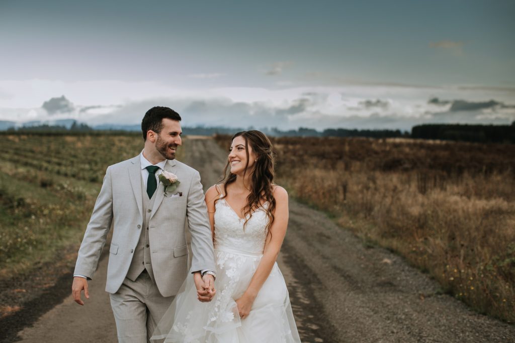 bride and groom walking on path, smiling